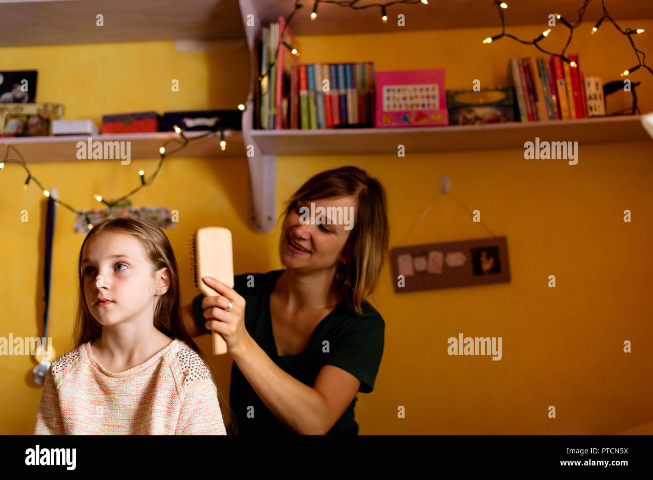 Mother combing daughters hair at home Stock Photo