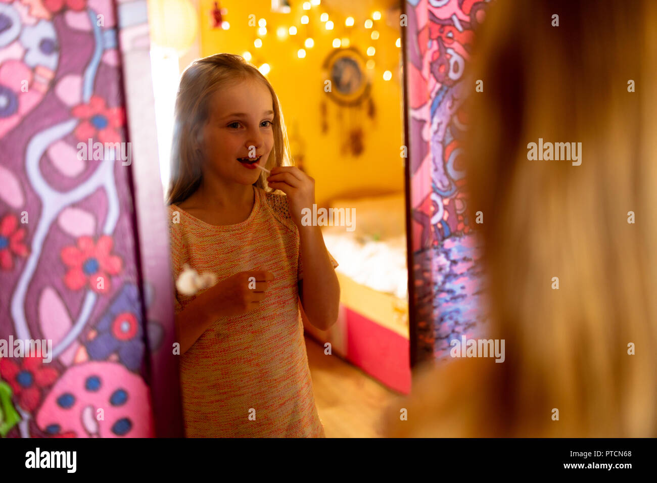 Girl looking in the mirror and applying red lipstick Stock Photo