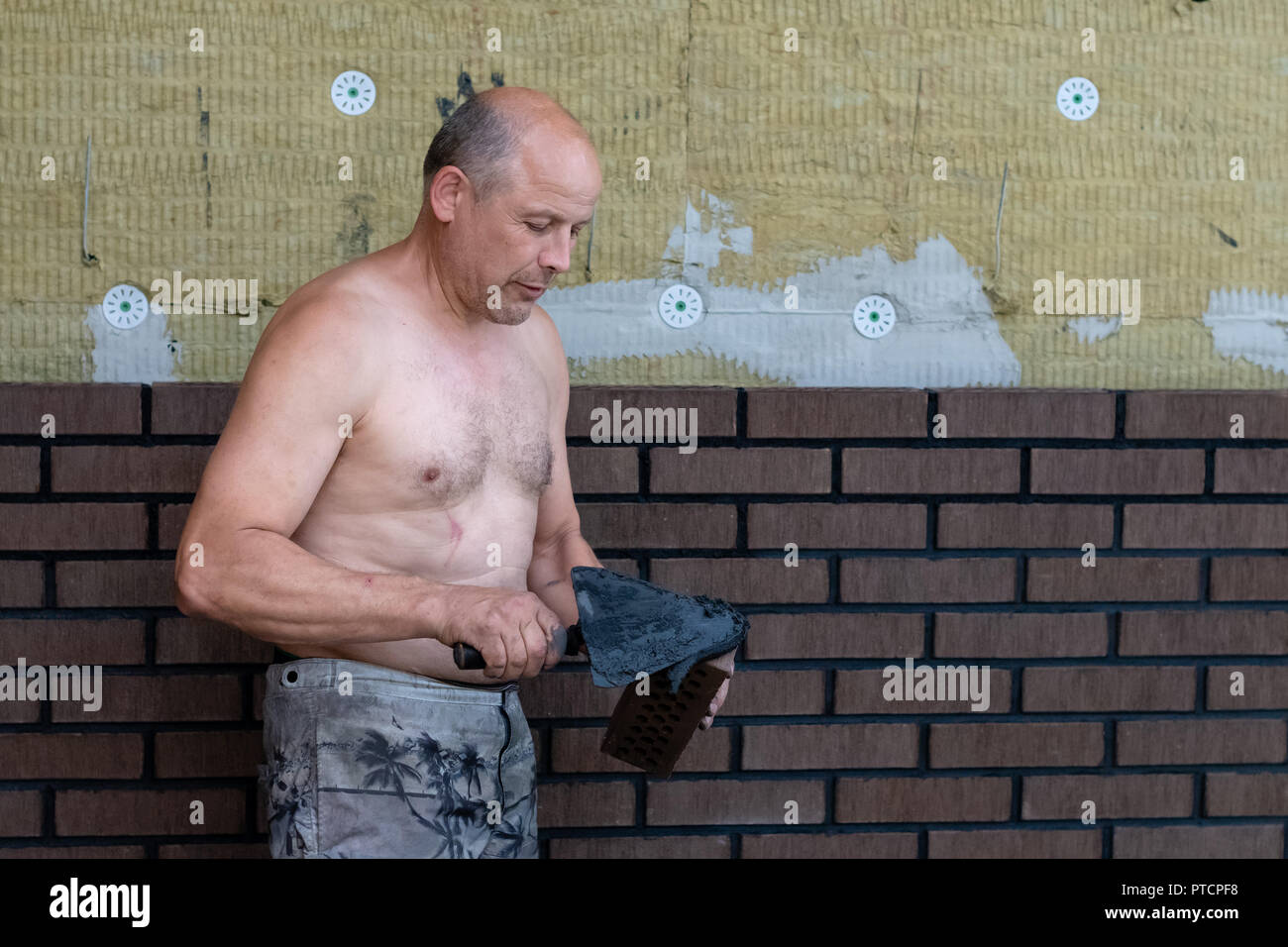 Bricklayer worker installing bricks on construction site. Stock Photo