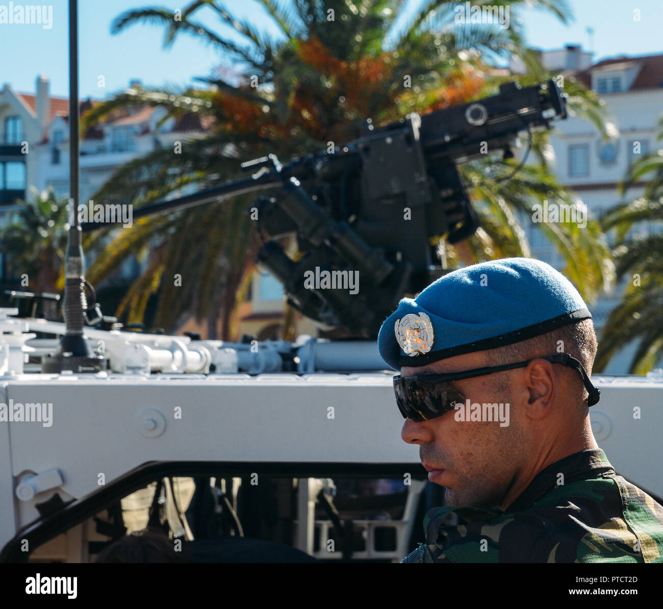 Close up of United Nationals peacekeeping soldier with blue beret and tank in background - keeping the peace concept in times of war Stock Photo
