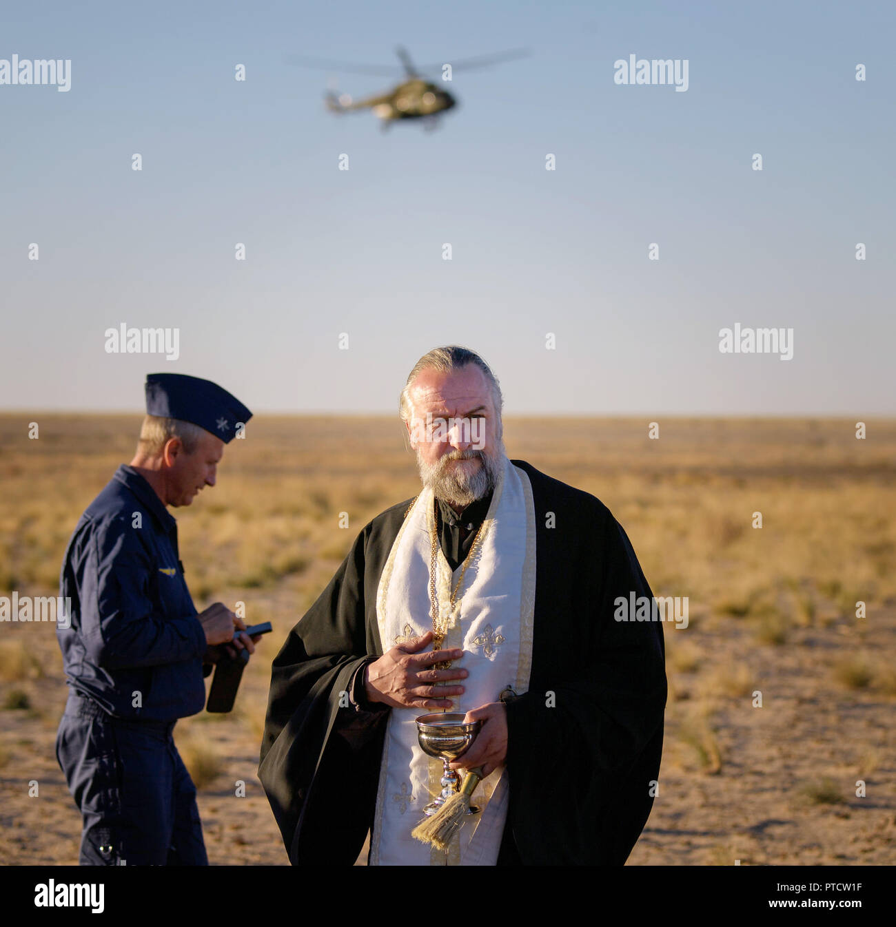 Russian Orthodox Priest, Father Alexander, watches over the landing zone after the International Space Station Expedition 56 crew members Ricky Arnold of NASA, Flight Engineer and Soyuz Commander Oleg Artemyev of Roscosmos, and Expedition 56 Commander Drew Feustel of NASA landed in the Russian Soyuz MS-08 spacecraft October 4, 2018 in Zhezkazgan, Kazakhstan. Stock Photo
