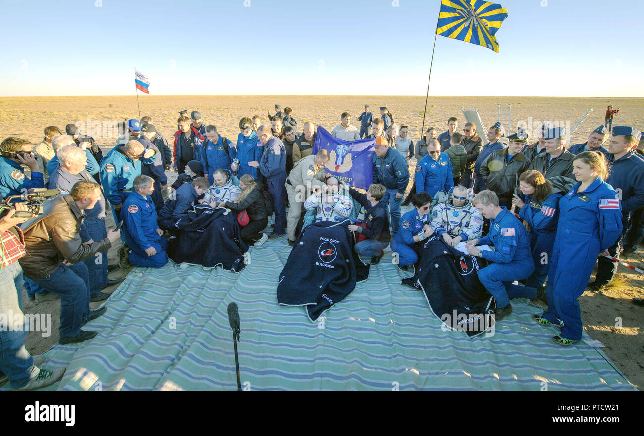 International Space Station Expedition 56 astronaut Ricky Arnold of NASA, left, Soyuz Commander Oleg Artemyev, center, and American astronaut Drew Feustel, rest outside the Russian Soyuz MS-08 spacecraft shortly after landing October 4, 2018 near Zhezkazgan, Kazakhstan. Stock Photo