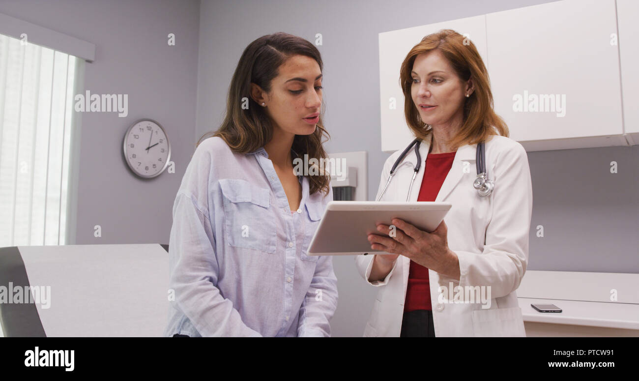 Mid aged medical doctor using portable tablet to review test results of patient Stock Photo