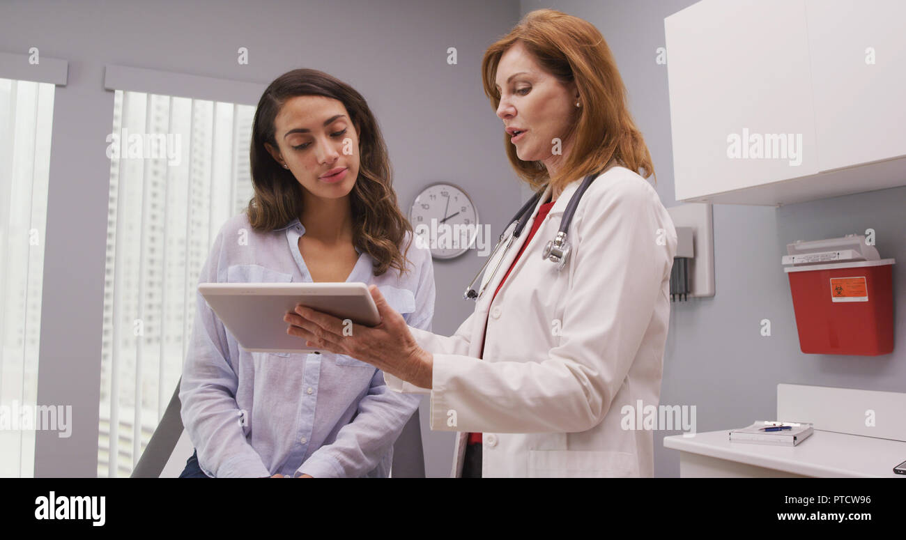 Mid aged medical doctor using portable tablet to review test results of patient Stock Photo