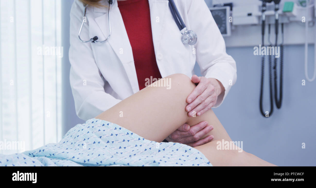 Young female woman having knee examined after sustaining injury in accident Stock Photo