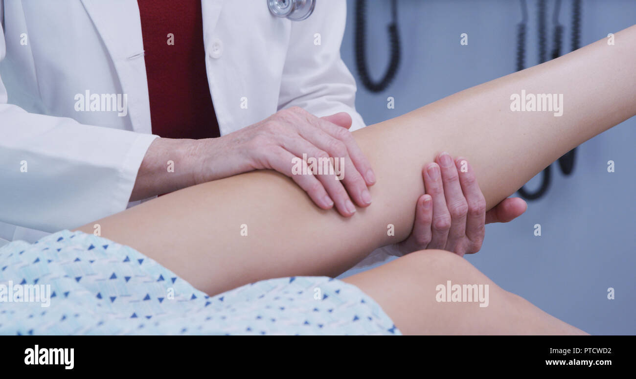 Young female woman having knee examined after sustaining injury in accident Stock Photo
