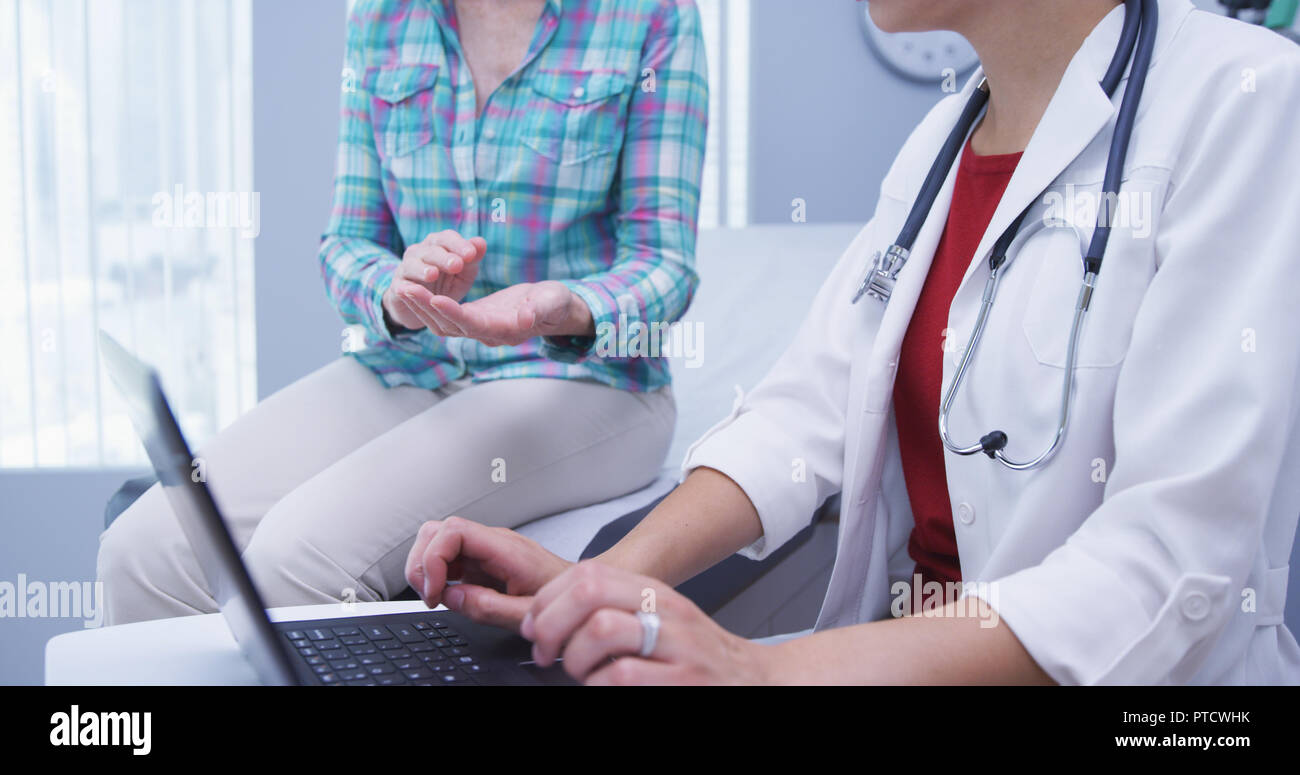 Tight shot of young doctor attending mid aged patient and using laptop Stock Photo