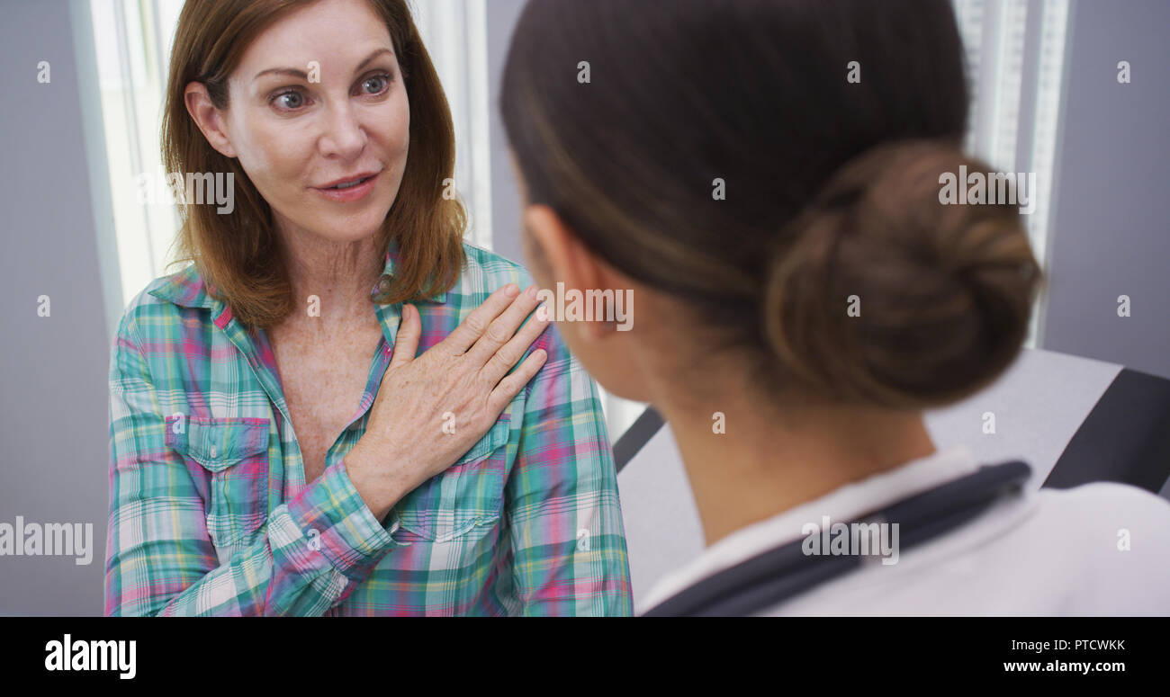 Close up of charming mid aged patient explaining to doctor her shoulder pain Stock Photo
