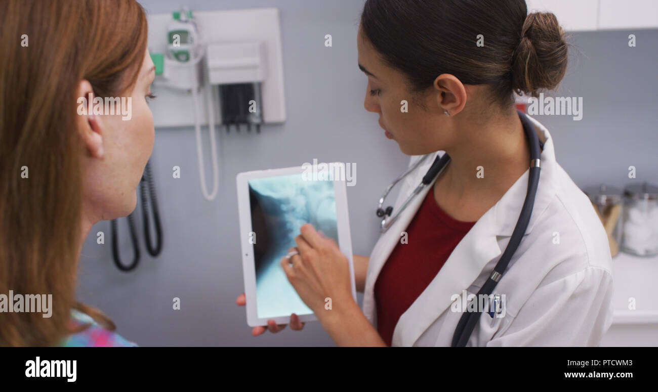 Portrait of young doctor using tablet to review x ray of female patients neck Stock Photo