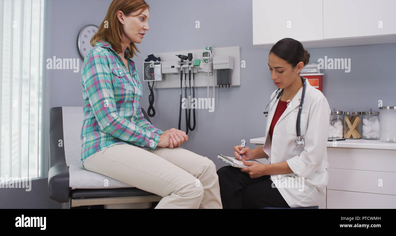 Mid aged caucasian woman consulting with doctor about future health condition Stock Photo