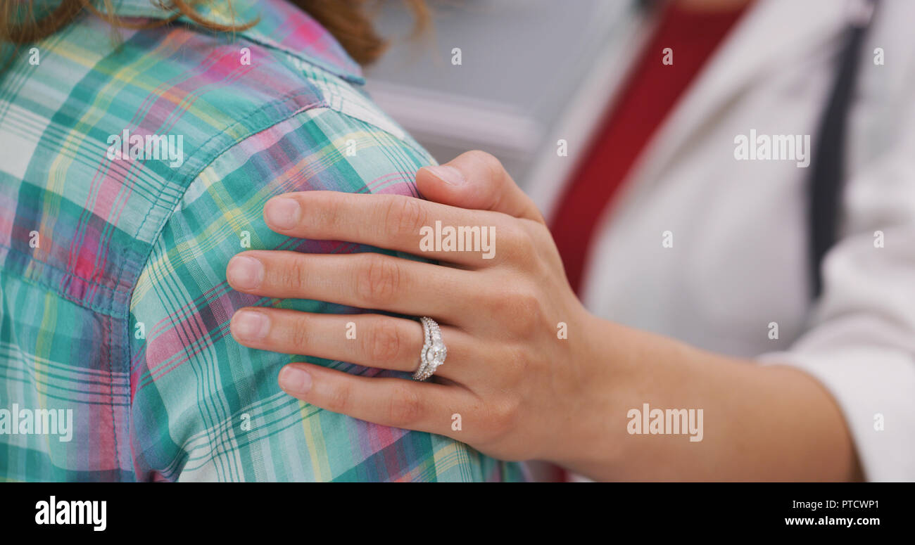 Close up of young married doctor placing her hand on patients shoulder Stock Photo