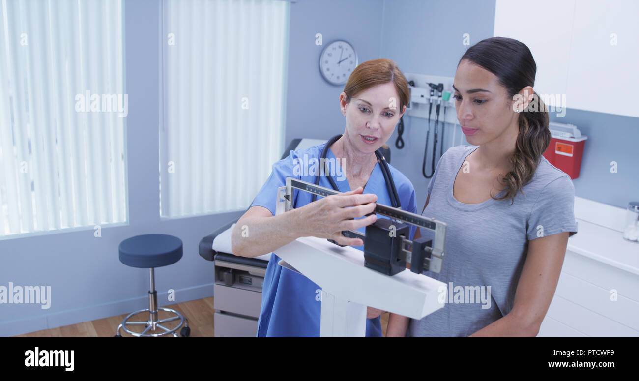 Charming middle aged nurse using scale to measure weight o photo