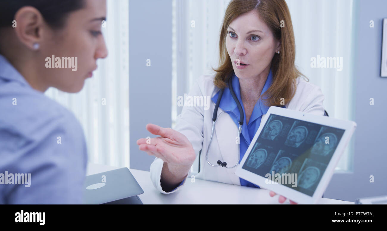 Young patient consulting with doctor over ct-scan indoors medical clinic Stock Photo