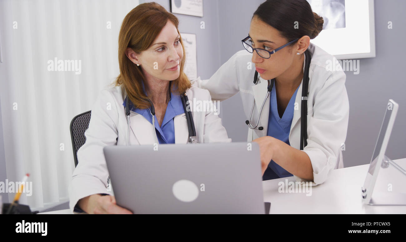 Two medical doctors using notebook computer to discuss patients healh condition Stock Photo