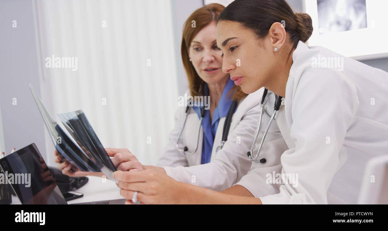 Young medical colleague discussing x rays with senior doctor in her office Stock Photo