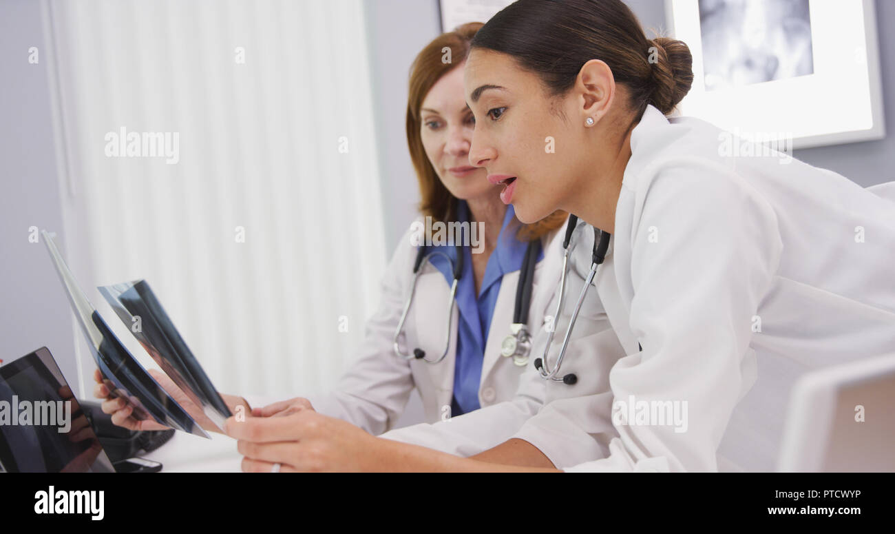 Young medical colleague discussing x rays with senior doctor in her office Stock Photo