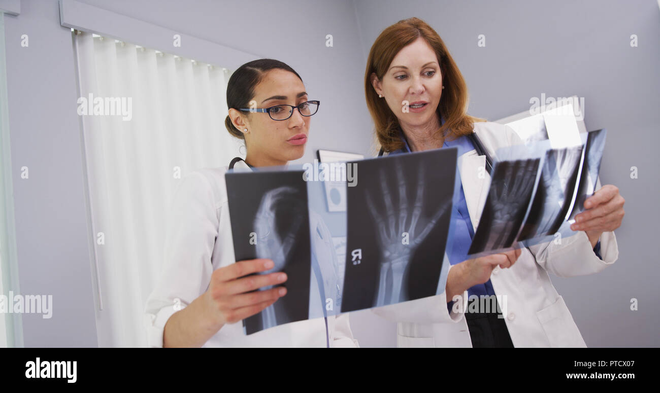 Close up of beautiful latina doctor speaking with senior colleague about xrays Stock Photo