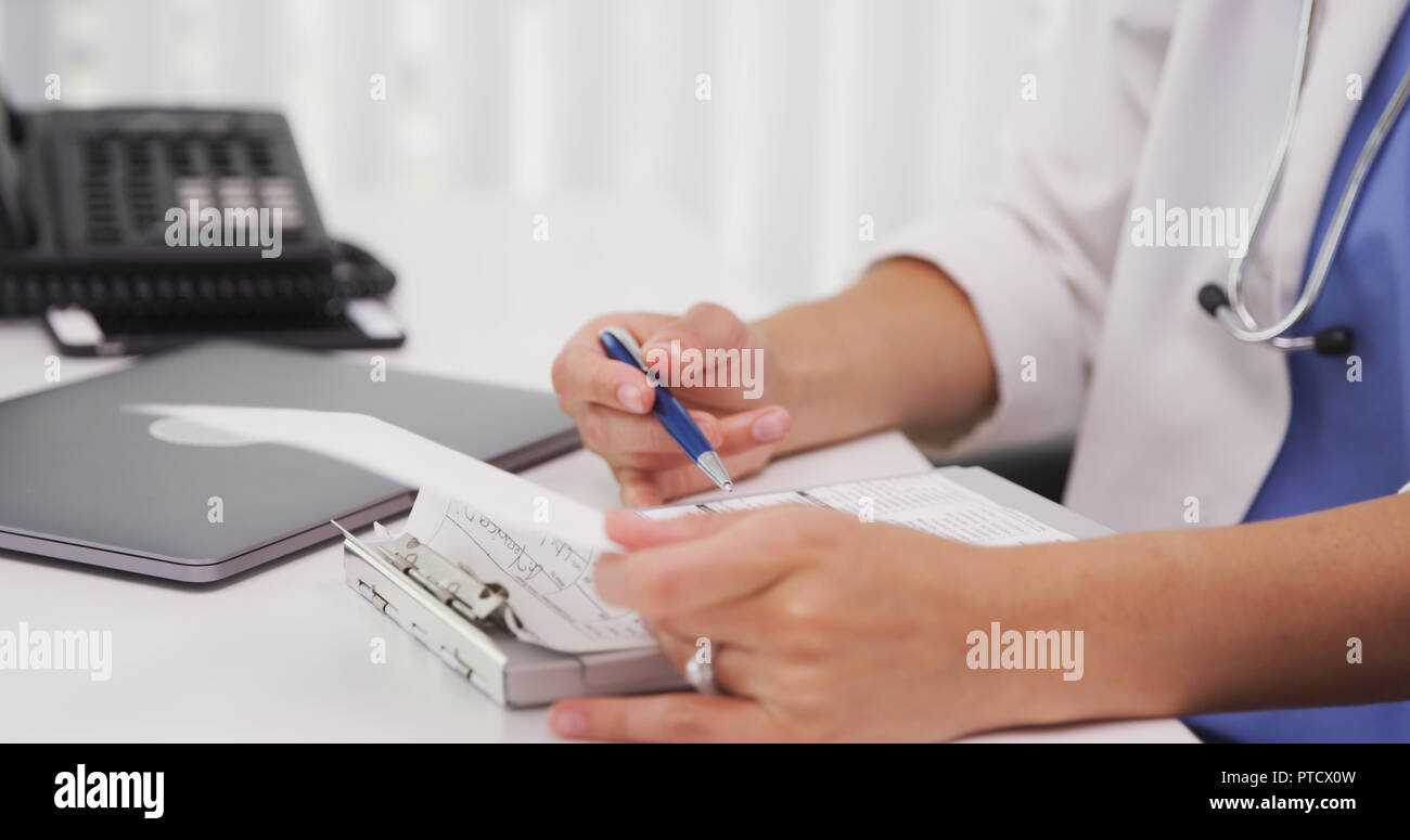 Close up of female licensed MD using clipboard inside her office Stock Photo