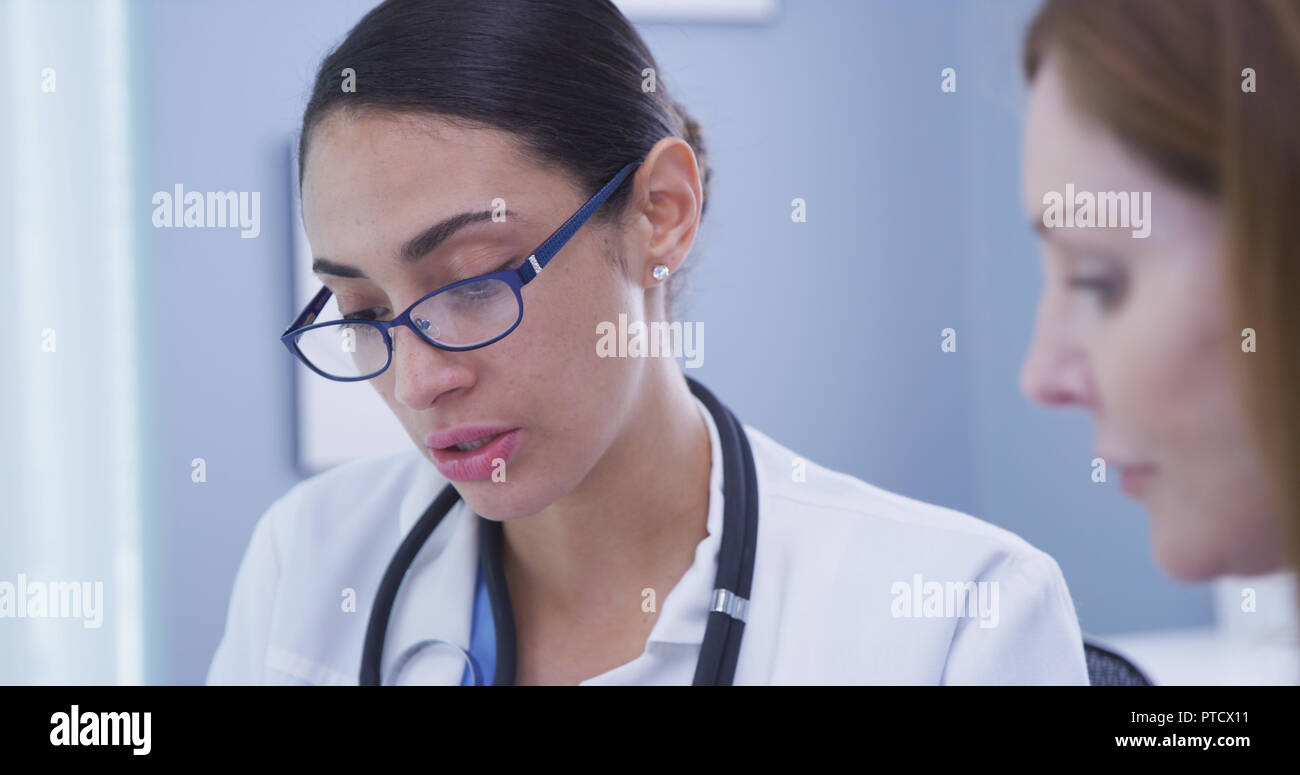 Close up of young attractive hispanic medical doctor talking with senior patient Stock Photo