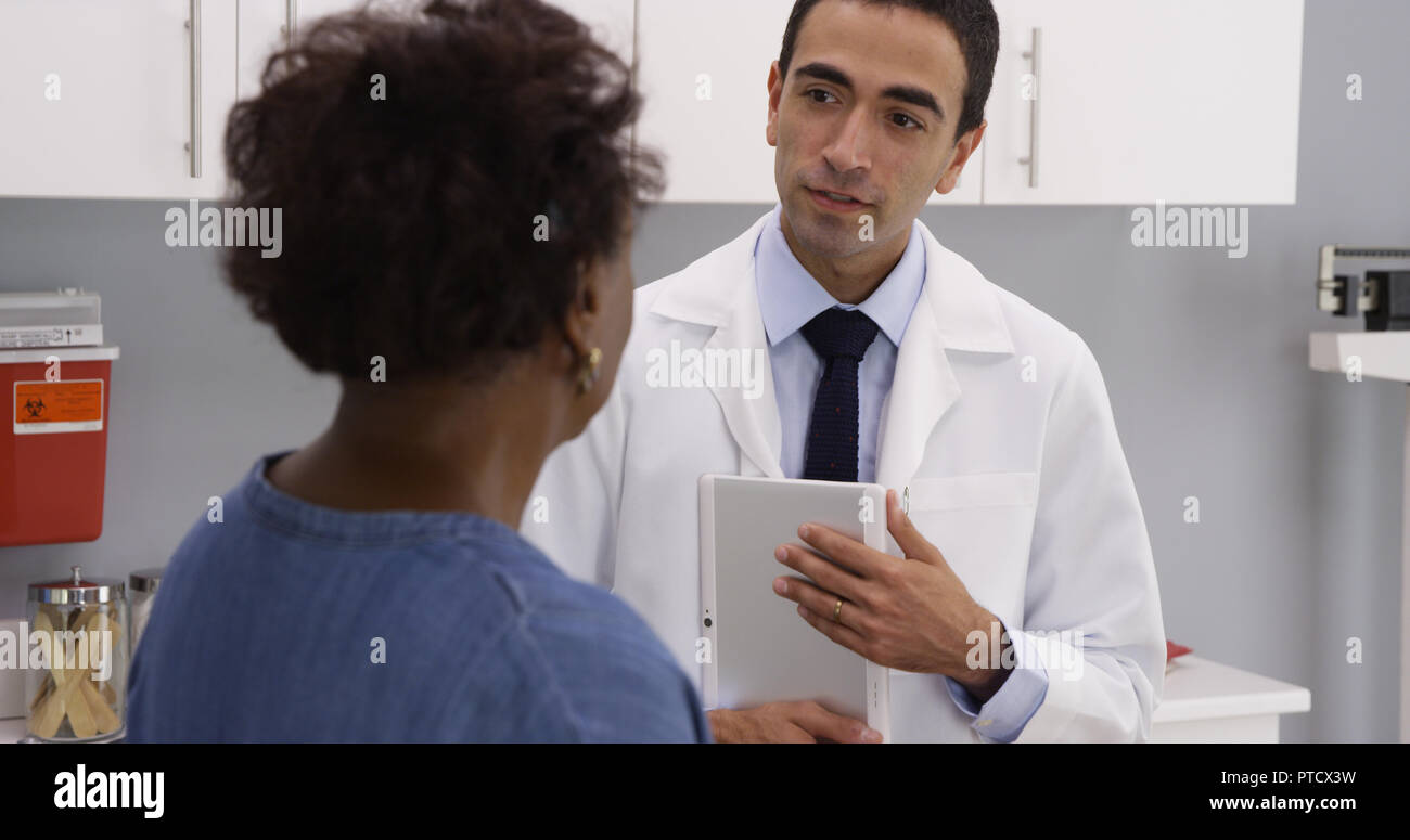 Charming young hispanic doctor using tablet to view patient medical file Stock Photo