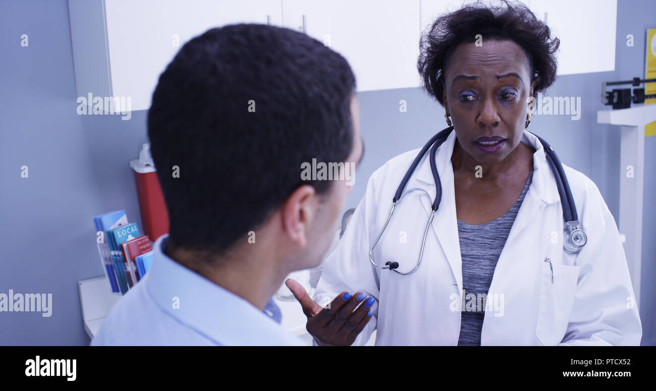 Senior African doctor using portable tablet to take notes of patients health Stock Photo