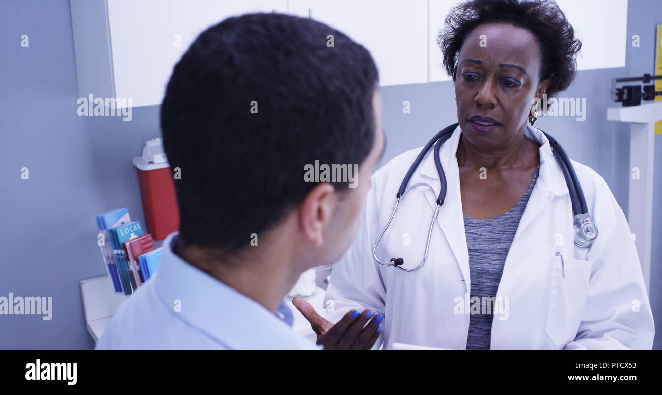 Senior African doctor using portable tablet to take notes of patients health Stock Photo
