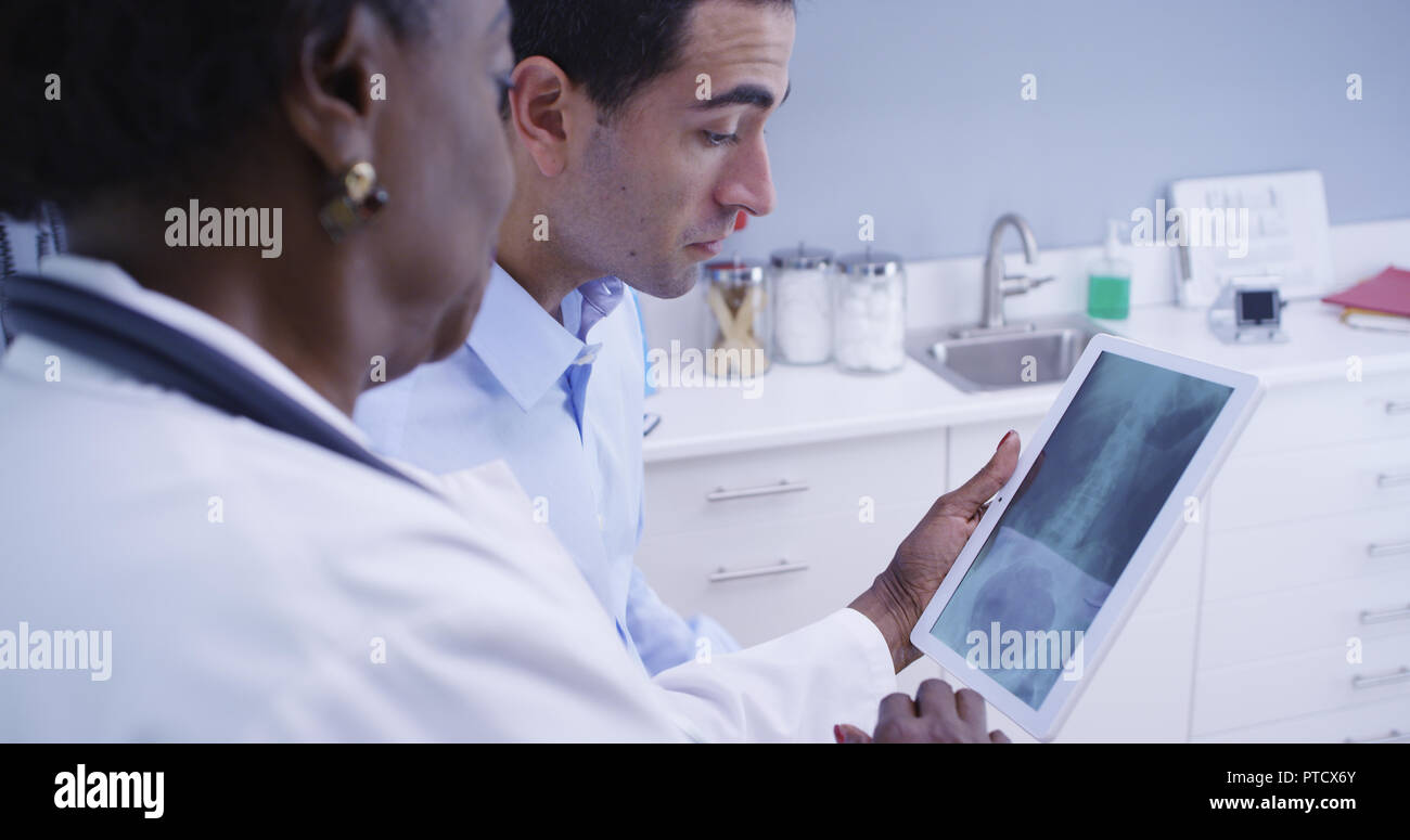 Young latino patient looking at x ray of his body on electronic notebook tablet Stock Photo