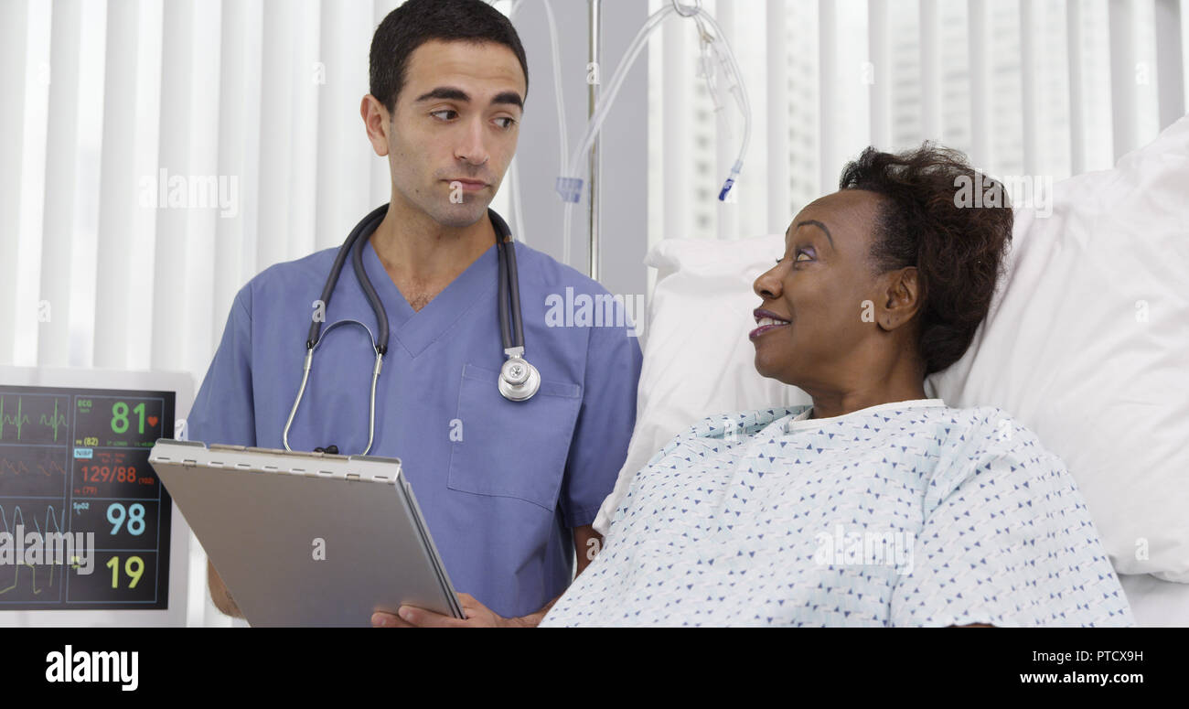 Young latino doctor consulting with mid aged African woman on her health history Stock Photo