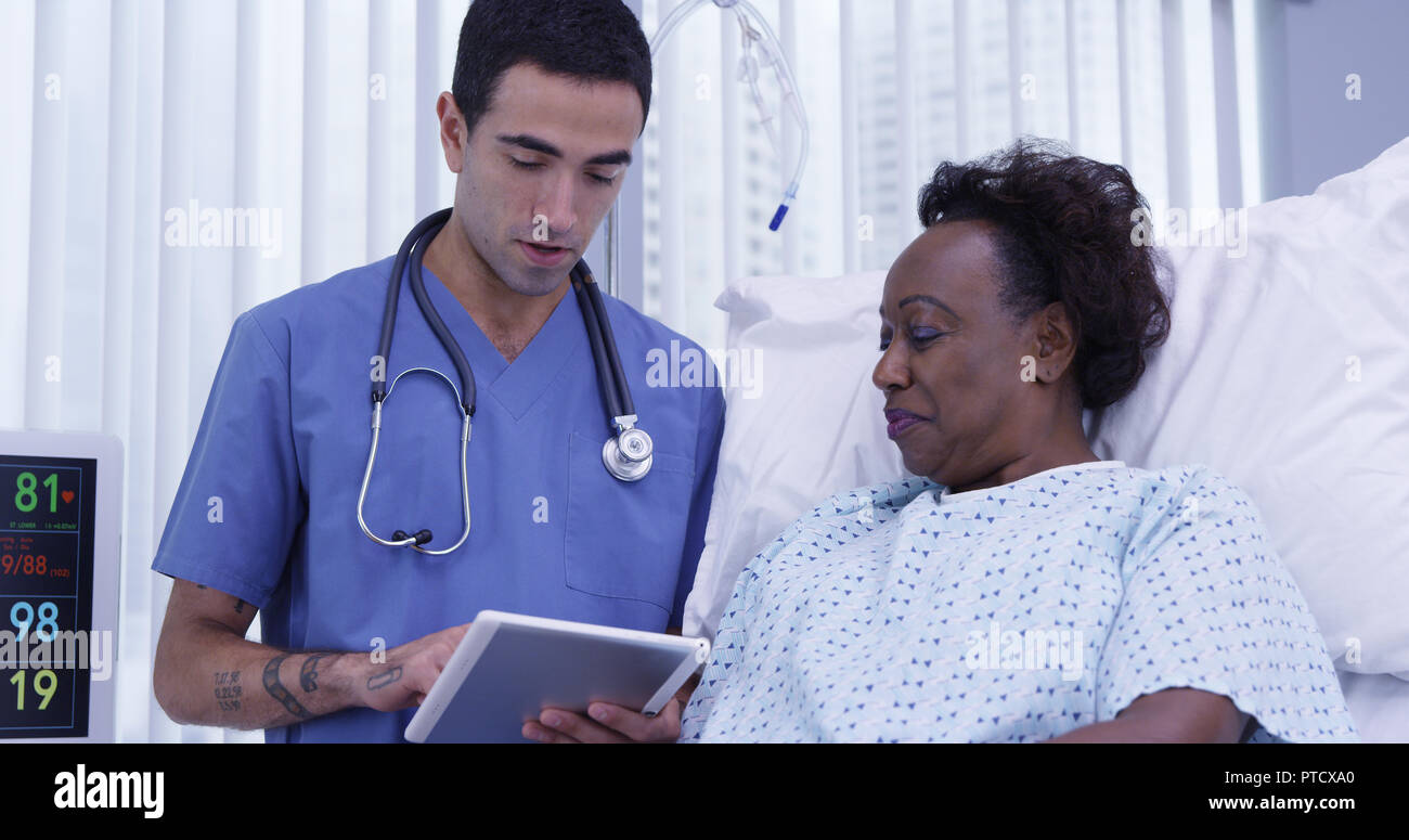 Portrait of young male MD using tablet to show patient her health condition Stock Photo