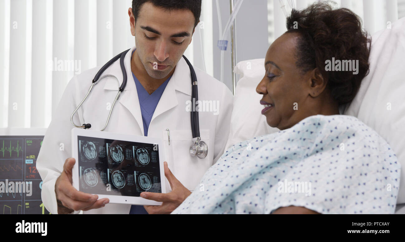 Portrait of hispanic medical doctor showing ct-scans on tablet to patient Stock Photo