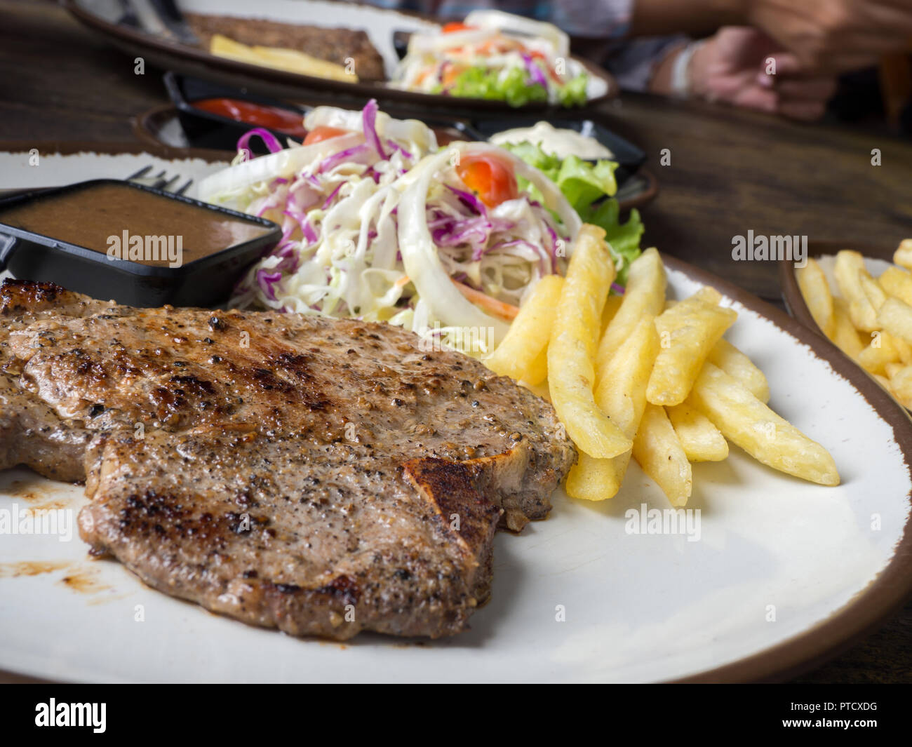 close up of Tbone steak with salt and pepper, golden french fries and
