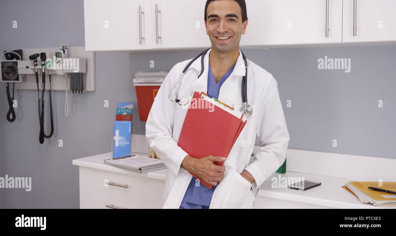 Happy male latino doctor holding patient folders and smiling at camera Stock Photo