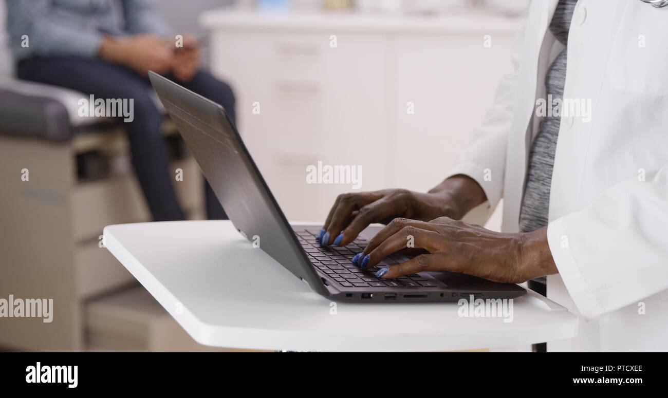 Close view of laptop computer and medical doctor typing notes Stock Photo