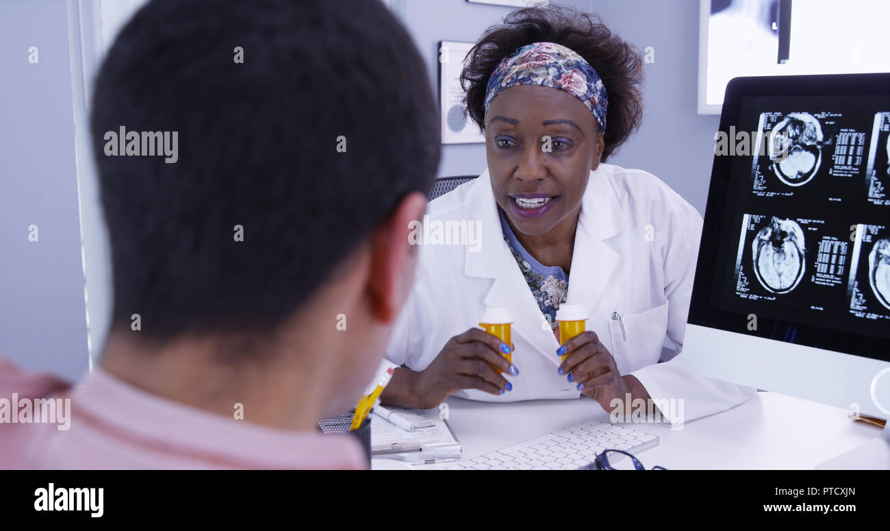 Senior African doctor prescribing medication to male patient with brain anomaly Stock Photo