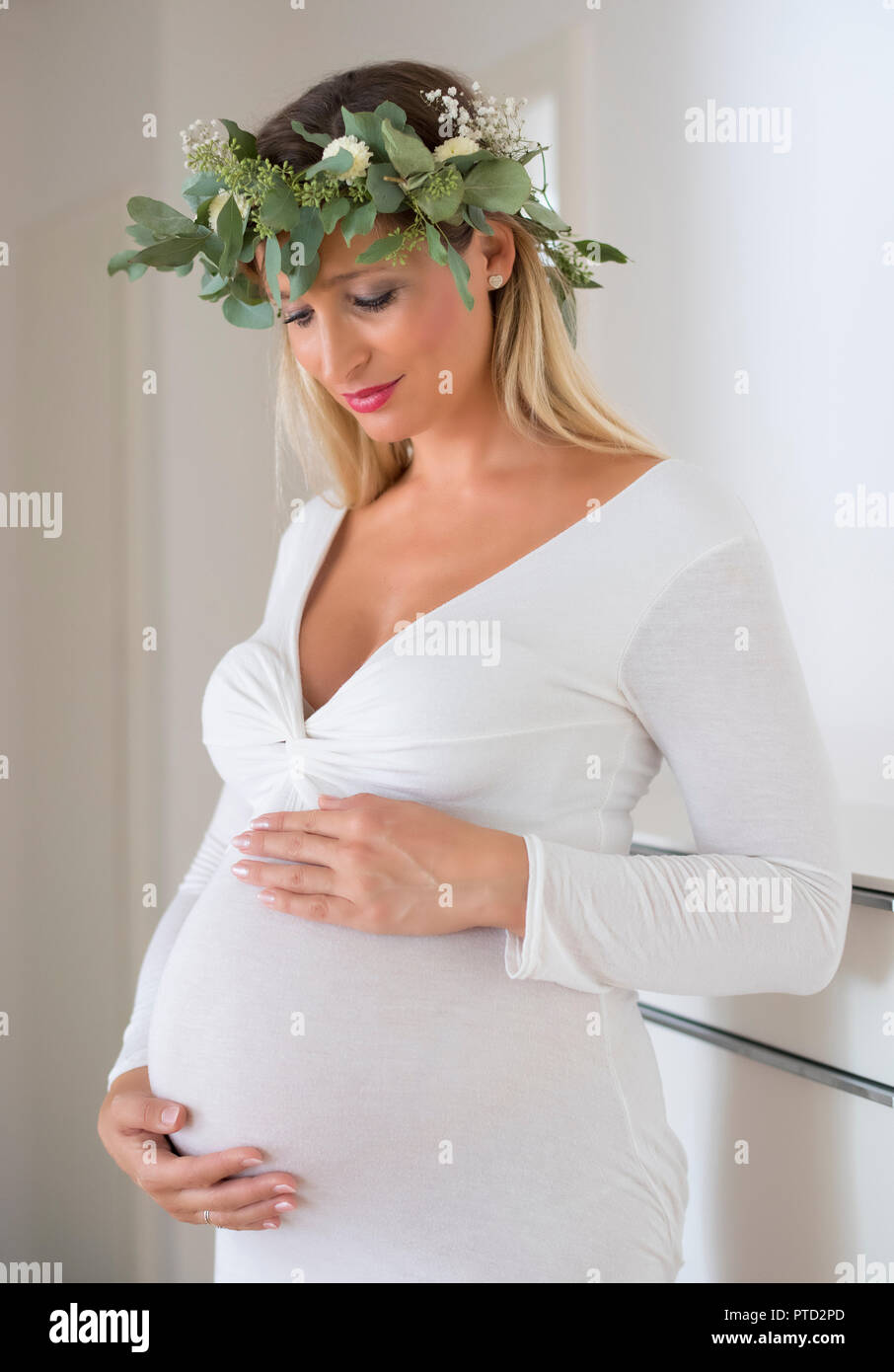 Woman, bride, with wreath of flowers, nine months pregnant, holding pregnat belly with her hands, Germany Stock Photo