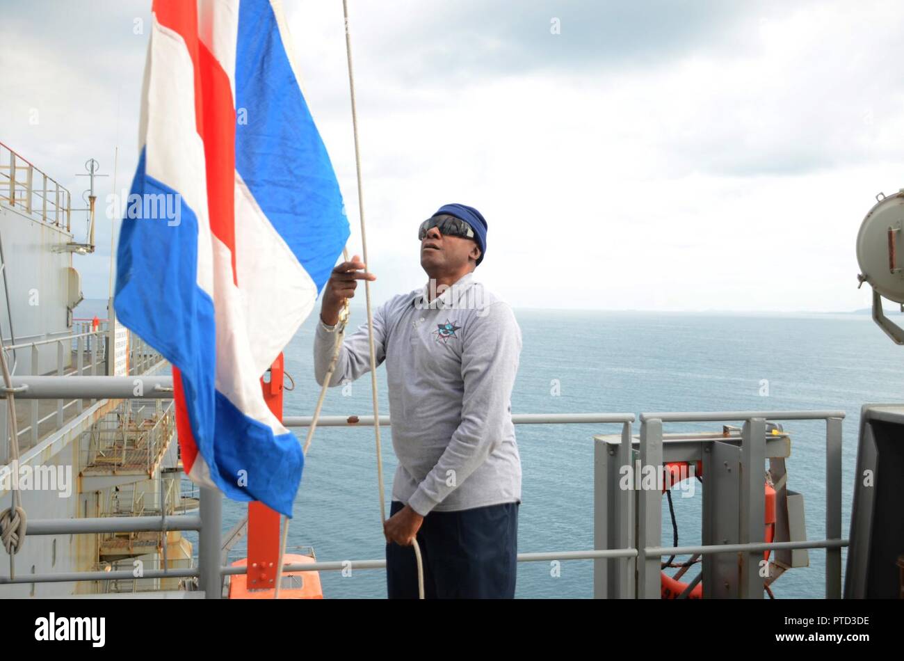 NOUMEA, New Caledonia (July 11, 2017) Willie Watkins, Able-Bodied Seaman aboard USNS Sacagawea (T-AKE 2), raises navigational flags during sea and anchor detail for the ships outboard journey from New Caledonia during Koa Moana 17, July 11. Koa Moana 17 is designed to improve theater security, and conduct aw enforcement and infantry training in the Pacific region in order to enhance interoperability with partner nations. Stock Photo