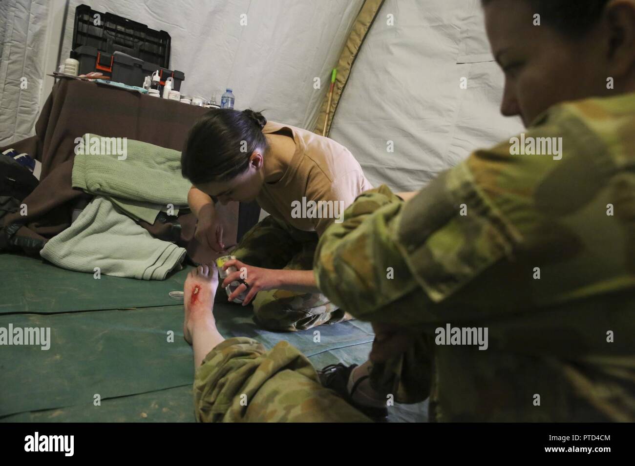 Sergeant Jolene Salter, a  medic with 3rd Health Support Battalion, 17th Combat Service Support Brigade, uses special-effects makeup to create a simulated foot injury on Pvt. Sarah Williams, a medic with 2nd General Health Battalion, 17th CSS Brigade, at Williamson Air Field, Shoalwater Bay Training Area, Queensland, Australia, July 8, 2017 during Talisman Saber 17. Australian Army soldiers with 17th CSS Brigade conducted a mass-casualty exercise at Williamson Air Field hospital to practice Role 2 advanced trauma care and procedures that are used in a deployed environment. Exercises like Talis Stock Photo
