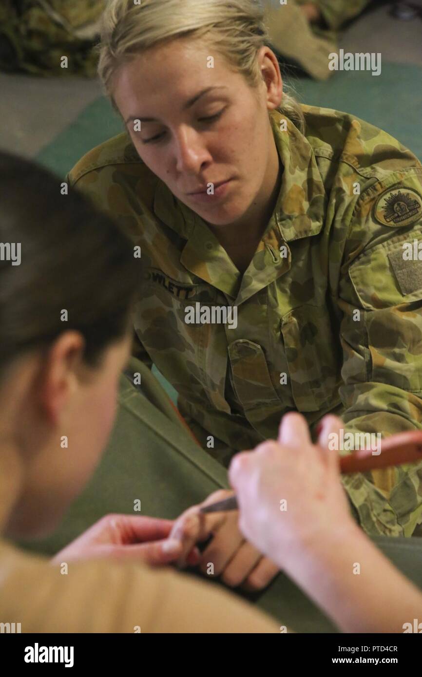 Private Sarah Nixon, a medic with 2nd General Health Battalion, 17th Combat Service Support Brigade, watches as Sergeant Jolene Salter, a medic with 3rd Health Support Battalion, 17th CSS Brigade, uses special-effects makeup to create a simulated hand injury at Williamson Air Field, Shoalwater Bay Training Area, Queensland, Australia, July 8, 2017 during Talisman Saber 17. Australian Army soldiers with 17th CSS Brigade conducted a mass-casualty exercise at Williamson Air Field hospital to practice Role 2 advanced trauma care and procedures that are used in a deployed environment. Exercises lik Stock Photo