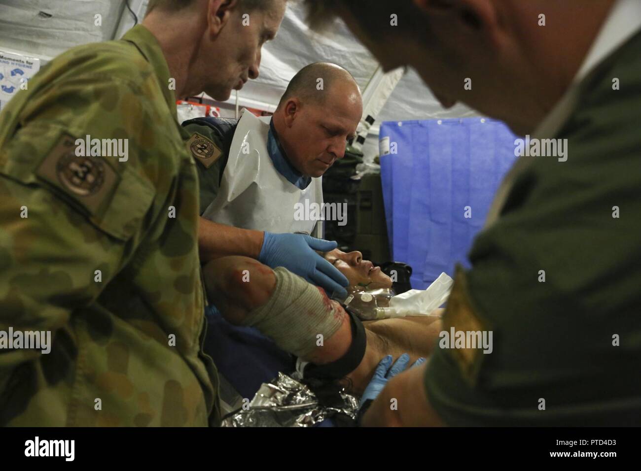 Australian Army medics with 17th Combat Service Support Brigade evaluate a patient with a simulated gunshot wound during a mass casualty exercise at Williamson Air Field, Shoalwater Bay Training Area, Queensland, Australia, July 8, 2017 during Talisman Saber 17. Soldiers with 17th CSS Brigade conducted a mass-casualty exercise at Williamson Air Field hospital to practice Role 2 advanced trauma care and procedures that are used in a deployed environment. Exercises like Talisman Saber provide effective and intense training to ensure our forces are capable, interoperable, deployable on short noti Stock Photo