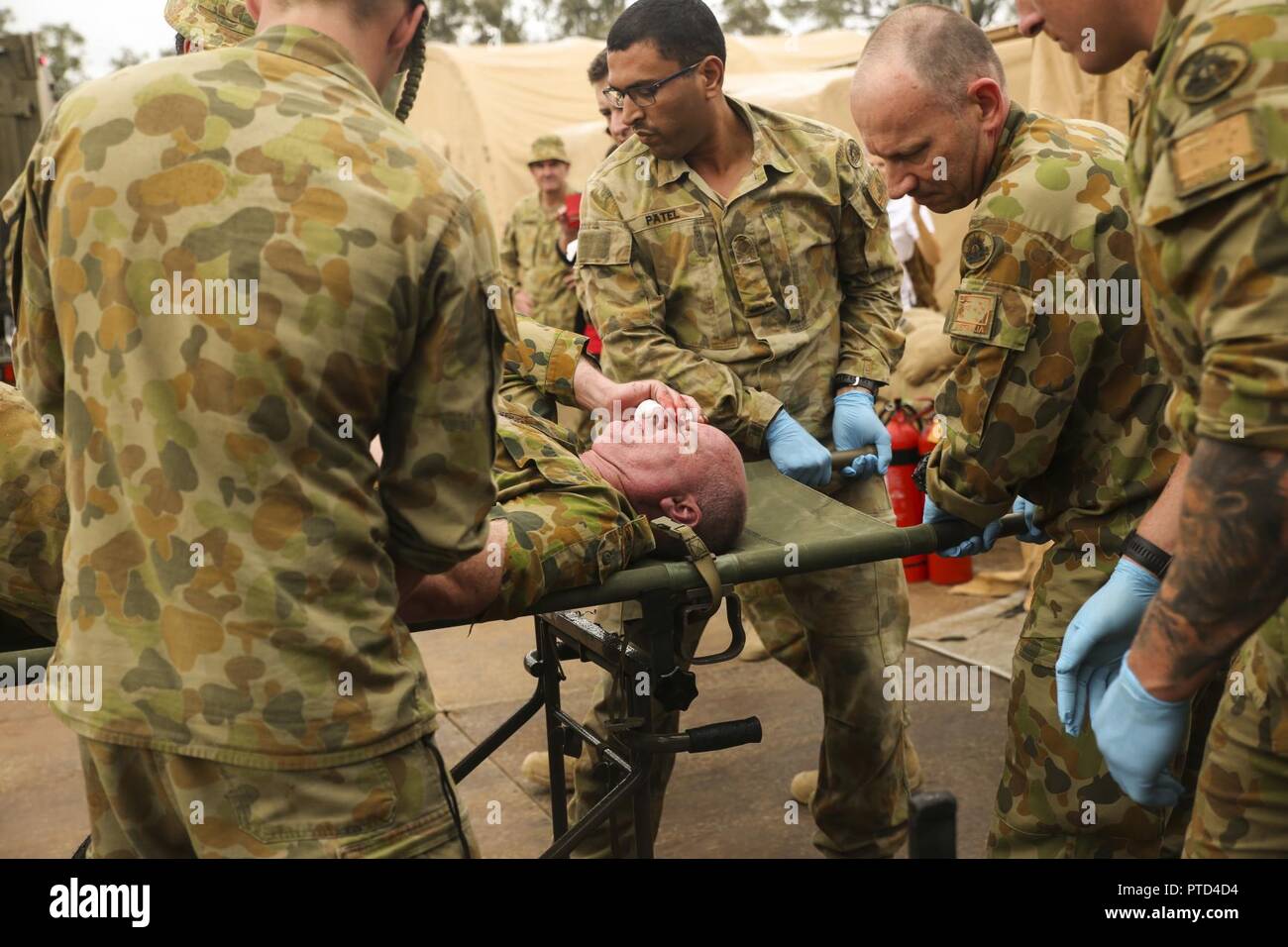 Australian Army medics with 17th Combat Service Support Brigade unload a patient with a simulated shrapnel wound from an ambulance during a mass casualty exercise at Williamson Air Field, Shoalwater Bay Training Area, Queensland, Australia, July 8, 2017 during Talisman Saber 17. Soldiers with 17th CSS Brigade conducted a mass-casualty exercise at Williamson Air Field hospital to practice Role 2 advanced trauma care and procedures that are used in a deployed environment. Exercises like Talisman Saber provide effective and intense training to ensure our forces are capable, interoperable, deploya Stock Photo
