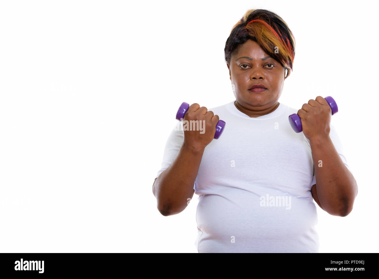 Studio shot of fat black African woman holding dumbbells ready f Stock Photo