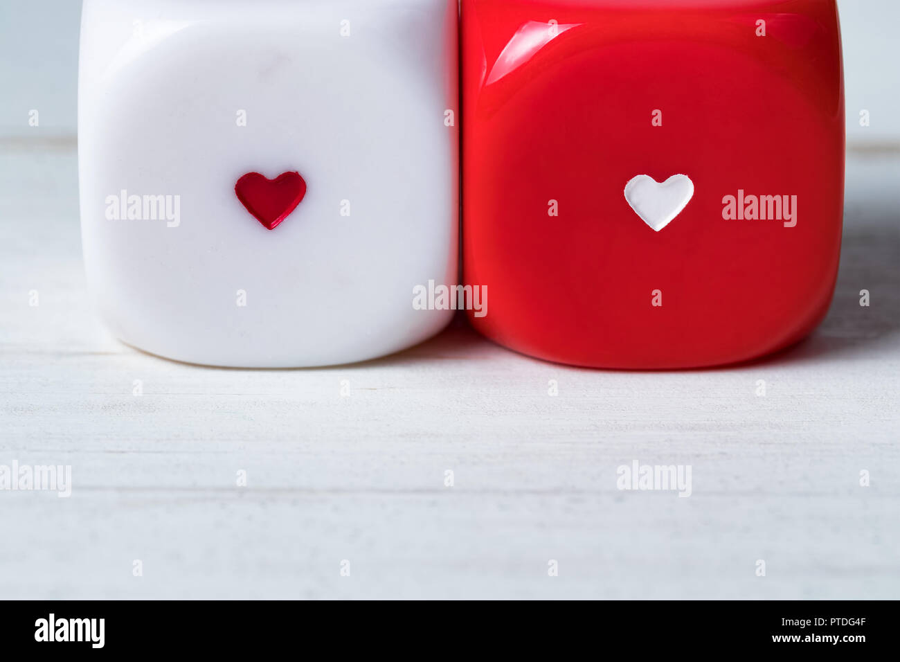 Two red and white Valentines Day heart dice on wooden background. Copy space on the bottom. Stock Photo