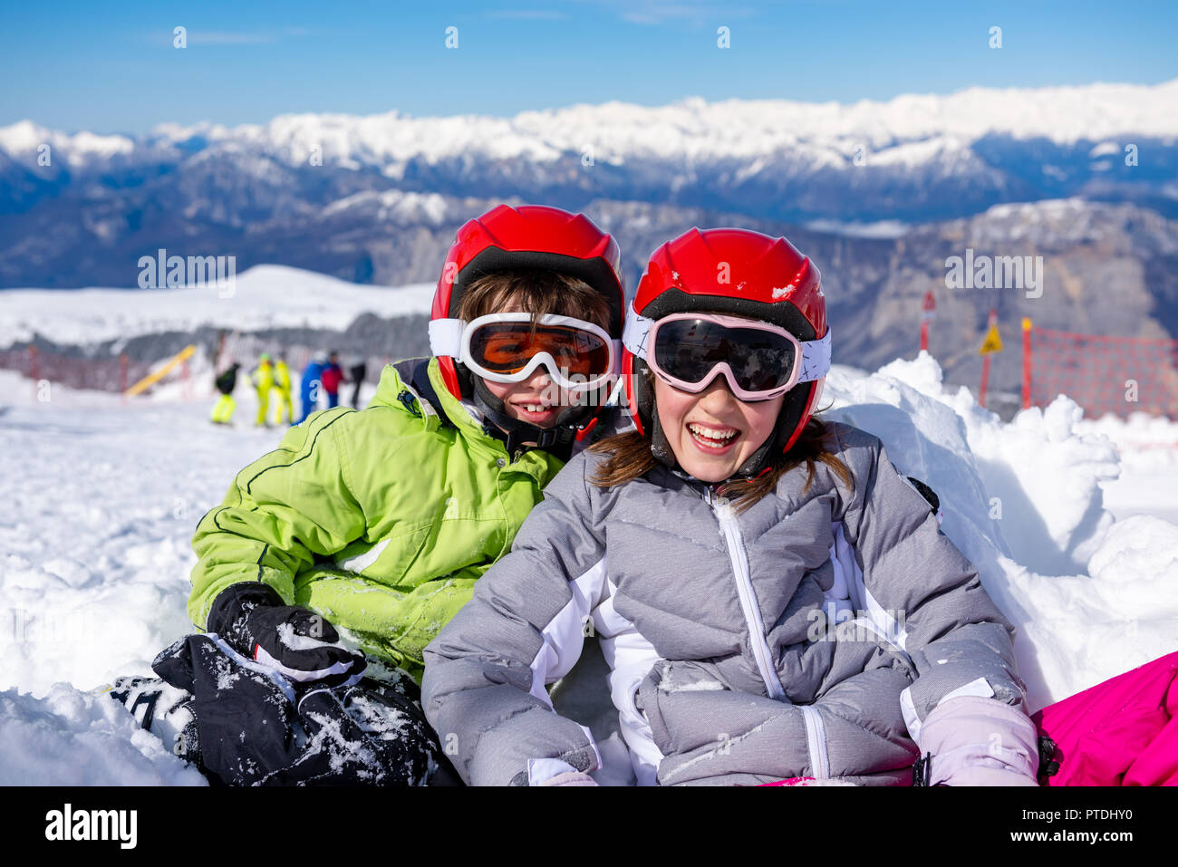 Children sitting on the ski slopes playing in the snow Stock Photo