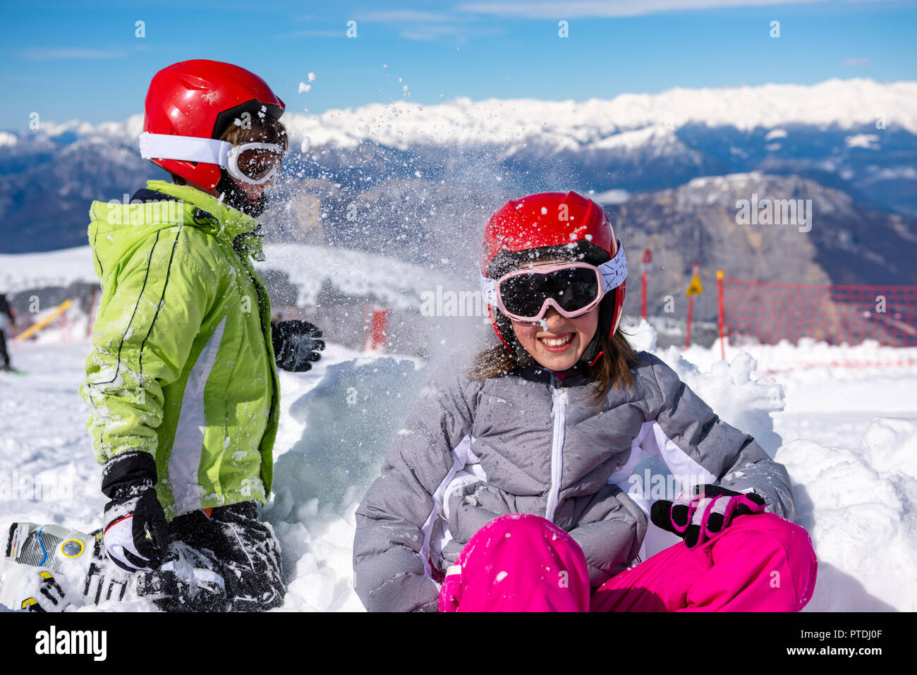 Children sitting on the ski slopes playing in the snow Stock Photo