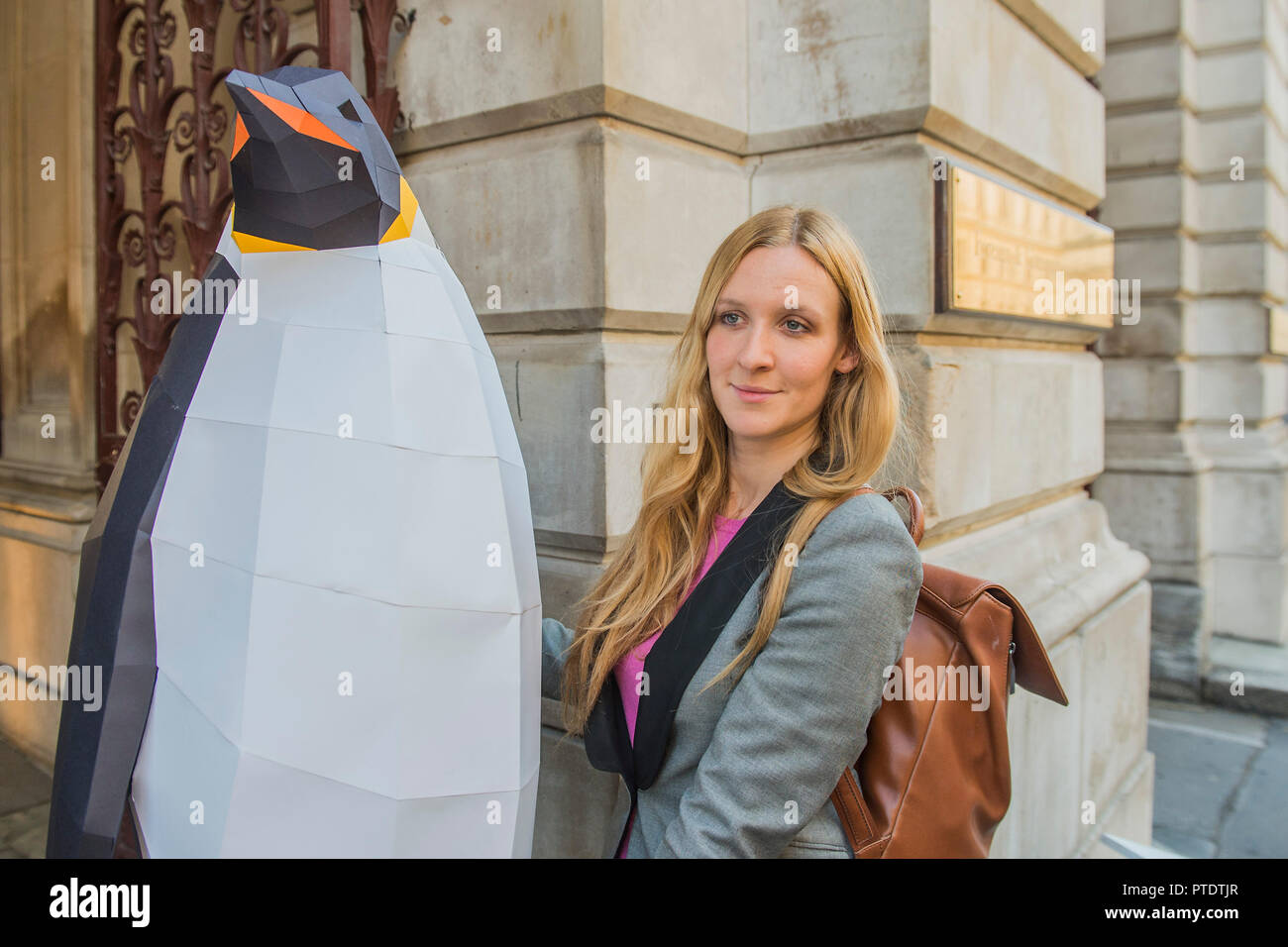 London, UK. 9th October, 2018. A Greenpeace spokesperson carries the penguin in to security - Gillian Anderson, Greenpeace Antarctic Ambassador, visits the Foreign & Commonwealth Office to deliver a petition calling for the creation of the largest protected area on Earth – a 1.8 million square kilometre Antarctic Ocean Sanctuary. Credit: Guy Bell/Alamy Live News Stock Photo