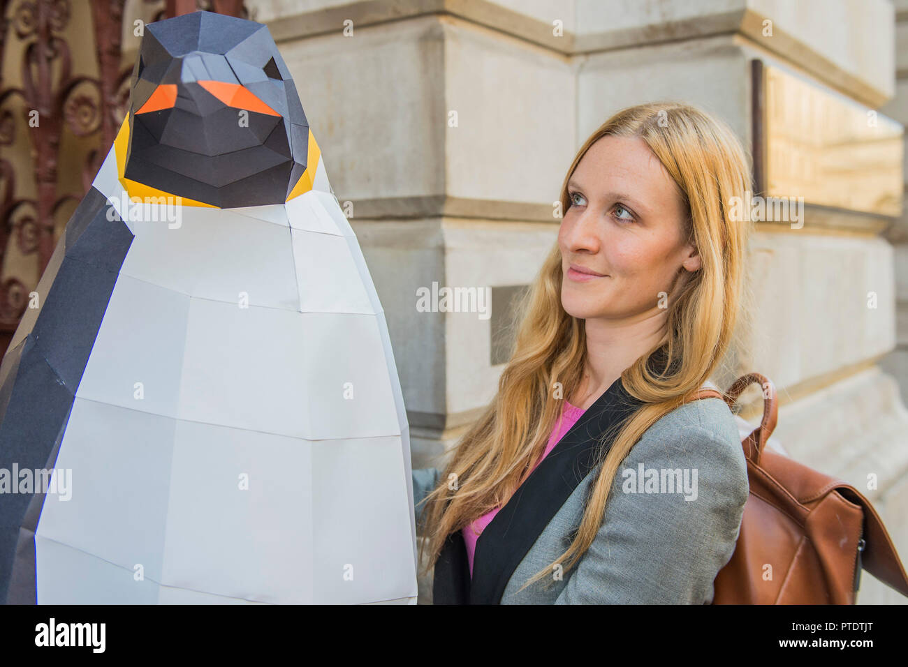London, UK. 9th October, 2018. A Greenpeace spokesperson carries the penguin in to security - Gillian Anderson, Greenpeace Antarctic Ambassador, visits the Foreign & Commonwealth Office to deliver a petition calling for the creation of the largest protected area on Earth – a 1.8 million square kilometre Antarctic Ocean Sanctuary. Credit: Guy Bell/Alamy Live News Stock Photo