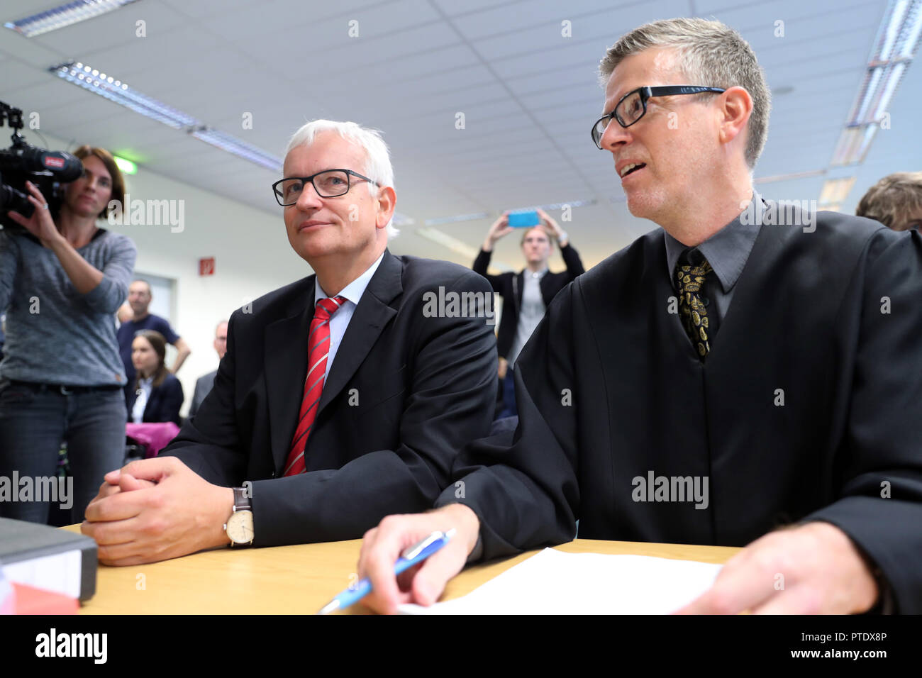 09 October 2018, Berlin: Jürgen Resch (l), the Federal Managing Director of Deutsche Umwelthilfe (DUH), sits in the Administrative Court room next to the lawyer Peter Kremer before the start of the oral hearing. The court is negotiating possible diesel driving bans in the capital. On many streets in Berlin the limit value for harmful nitrogen dioxide is exceeded. Photo: Jens Büttner/dpa-Zentralbild/dpa Stock Photo