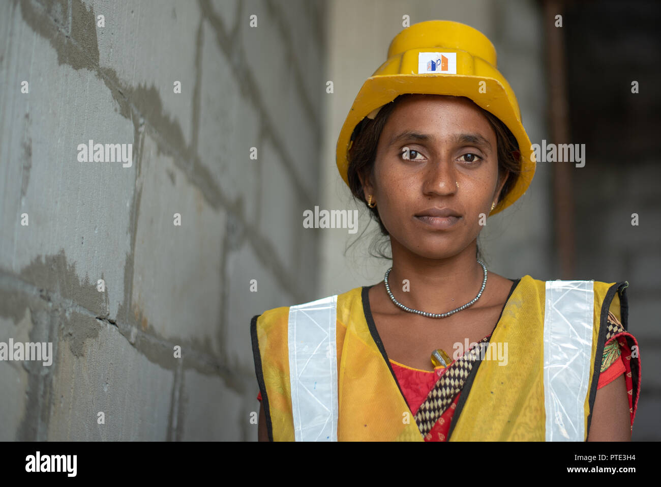 Woman labourer with the safety wear at building construction site. Urban cities in India is seeing lots of development projects. Stock Photo