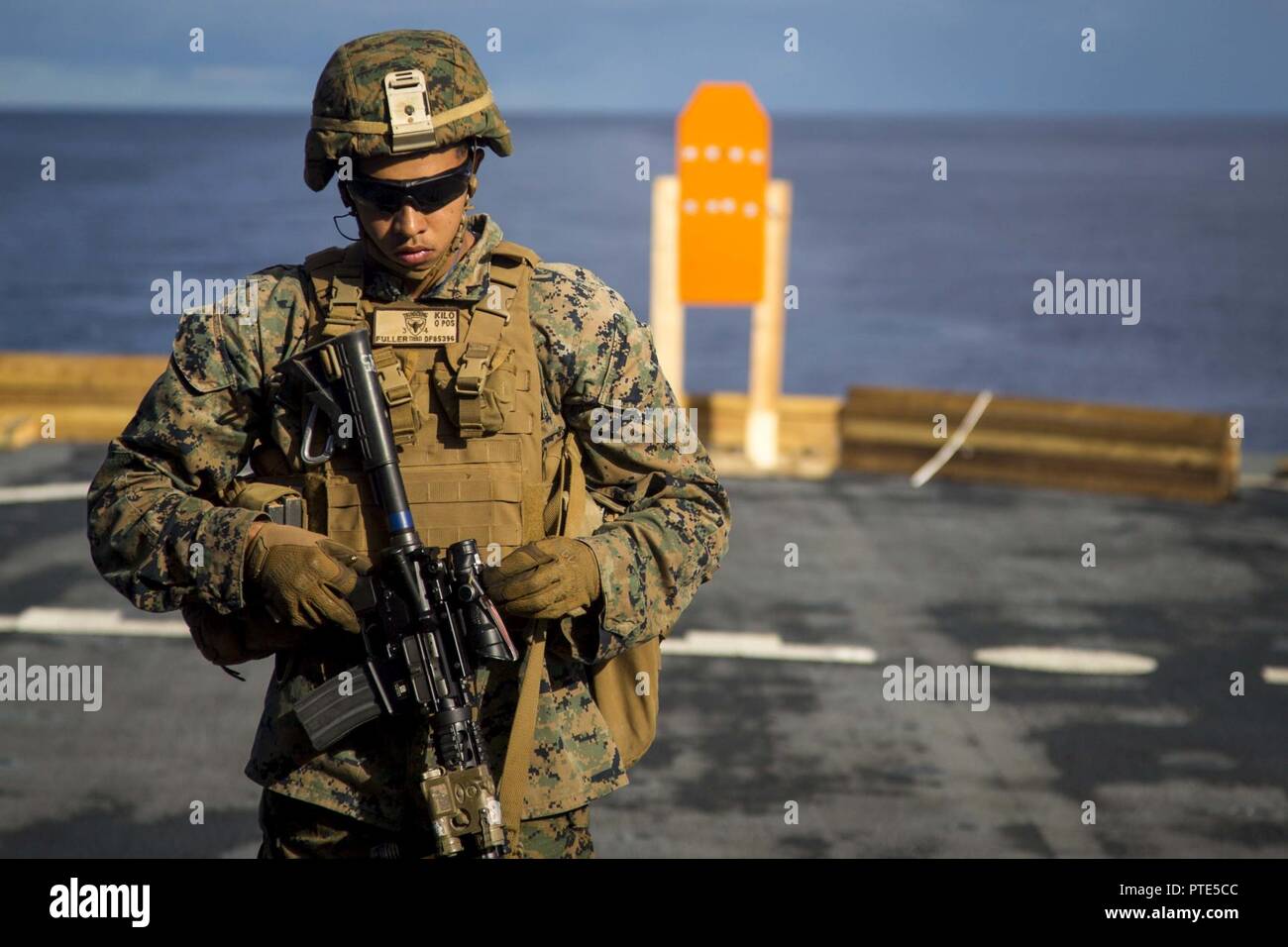 U.S. Marine Corps Lance Cpl. Daniel Fuller, an infantryman with Task Force Koa Moana 17, walks up range after analyzing his shot group during a live fire range aboard the USNS Sacagawea, July 13, 2017. Koa Moana 17 is designed to improve interoperability with our partners, enhance military-to-military relations, and expose the Marine Corps forces to different types of terrain for familiarity in the event of a natural disaster in the region. Stock Photo
