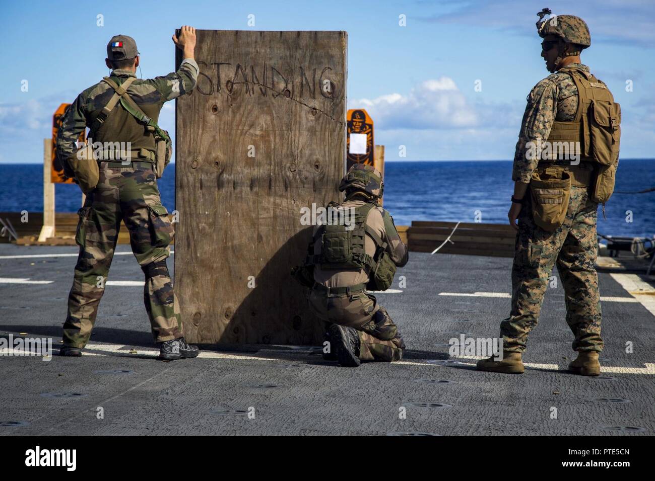 U.S. Marine Corps Sgt. Joseph Pritchard, right, an infantryman with Task Force Koa Moana 17, supervises a French soldier shoot at a target during a live fire range drill aboard the USNS Sacagawea, July 13, 2017. Koa Moana 17 is designed to improve interoperability with our partners, enhance military-to-military relations, and expose the Marine Corps forces to different types of terrain for familiarity in the event of a natural disaster in the region. Stock Photo
